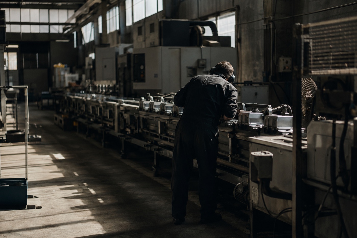 A worker on a manufacturing line, leaning in to inspect a component.